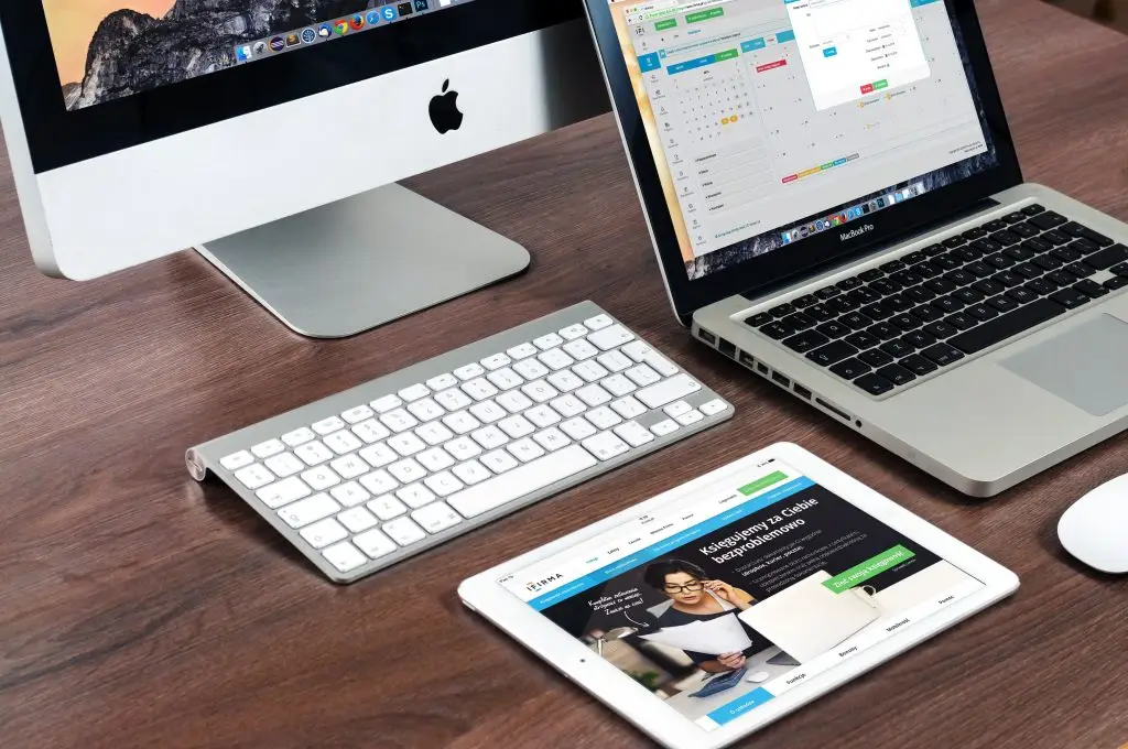 Web Develiopment A sleek office desk setup featuring Apple devices: iMac, MacBook, and iPad.