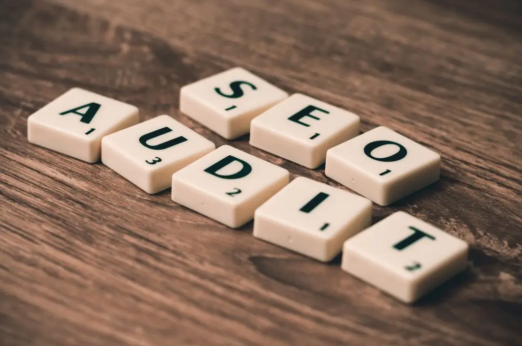 SEO Scrabble tiles spelling SEO Audit on wooden surface, symbolizing digital marketing strategies.